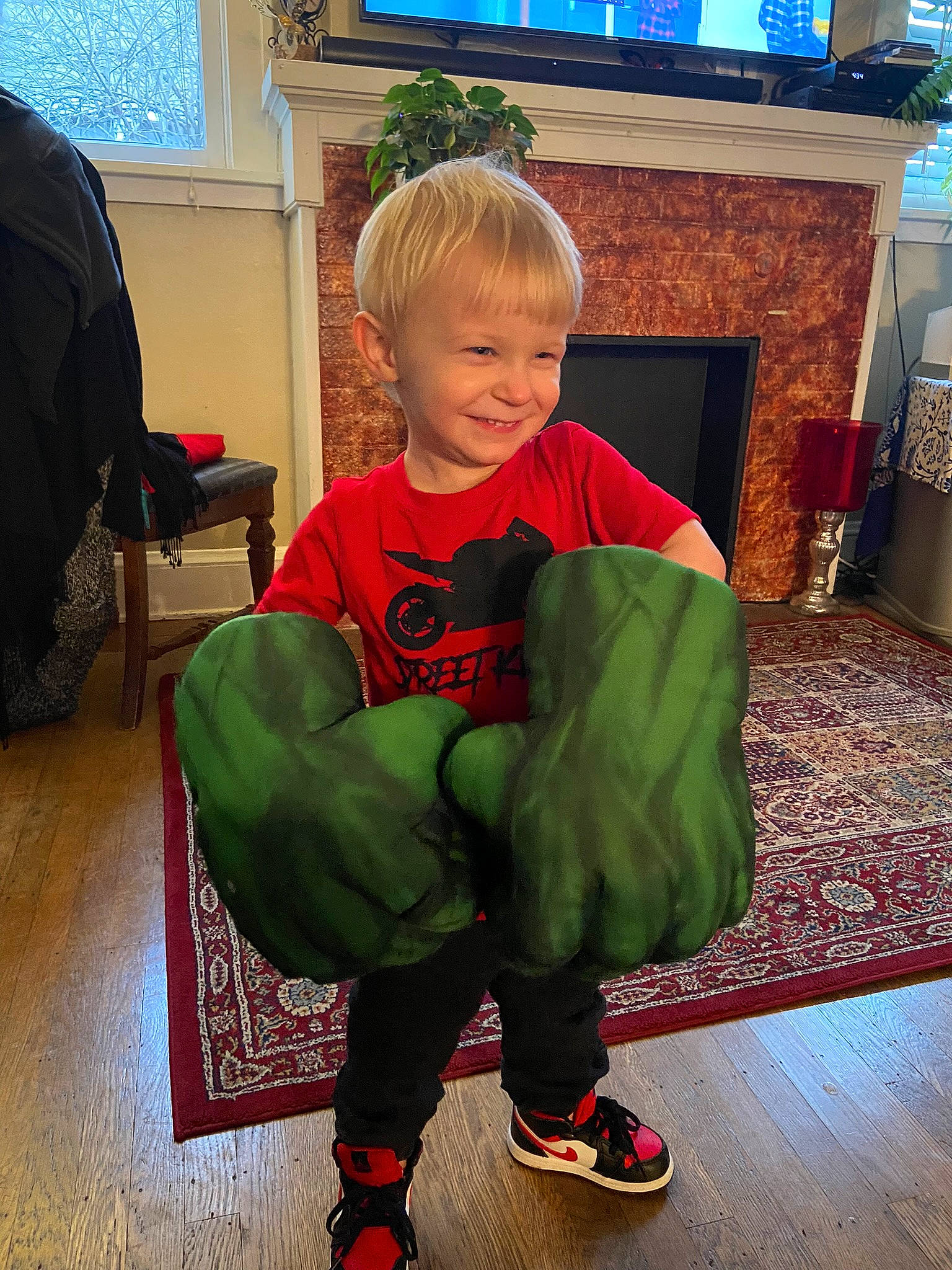 Jordan joined the competition — help win amazing prizes! baby_toddler_clothing, chair, christmas, comfort, floor, flooring, holiday, joy, knee, lap, leg, living_room, person, sleeve, smile, sneakers, sock, standing, t_shirt, television