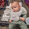 Sylas is registered to the contest to win money with this photo: baby, shopping_cart, bib, green_outfit, grocery_store, beverages, soda, cart, infant, child, floor, person, clothing, plastic_cup, blanket, hand, face, head, shopping, aisle