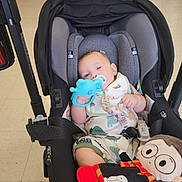 Sylas is registered to the contest to win money with this photo: baby, car_seat, teething_toy, plush_doll, dinosaur_outfit, floor, cabinet, baby_bib, infant, child, indoor, toy, seat_belt, cute, comfort, person, relaxed, holding, clothing, floor_tiles