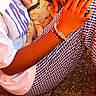 bracelet, casual, cat, checkered_pants, closeup, comfort, domestic_animal, floor, hands, kitten, lap, orange_tabby, outdoor, person, pet, resting, sitting, warm_light, white_shirt, young_cat