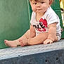 Caspain is registered to the contest to win money with this photo: baby, child, playground, sitting, curly_hair, white_shirt, expression, outdoor, metal_platform, green_background, cute, young_child, person, infant, portrait, summer, barefoot, skin, face, daylight