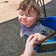 Caspain joined the competition — help win amazing prizes! toddler, child, swing, playground, hand_holding, smiling, outdoor, sunlight, tattoo, blue_swing, happy, person, casual_clothing, hair, face, expression, fun, recreation, park, daytime