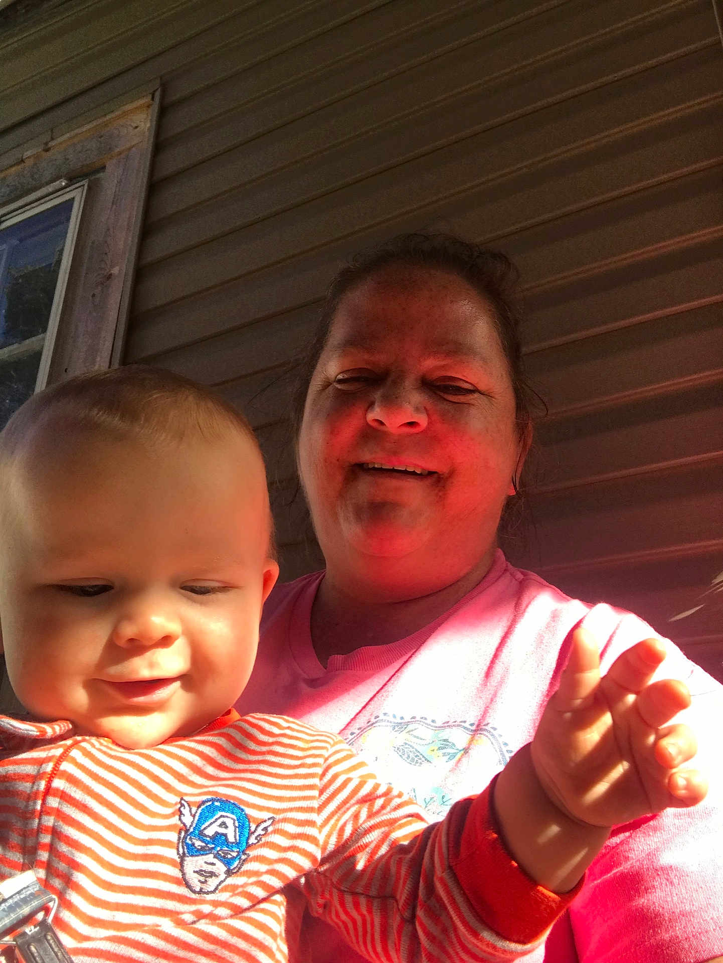 Hudson Kinley is registered to the contest to win money with this photo: baby, child, woman, smiling, striped_clothing, captain_america_logo, hand, porch, window, siding, sunlight, outdoor, person, face, happy, casual, daylight, closeup, family, holding