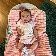 Frankie is registered to the contest to win money with this photo: baby, infant, pink_blanket, smiling, bow, cute, laying_down, socks, lace, pastel_clothing, wooden_floor, green_rug, indoor, child, happy, soft_texture, baby_girl, portrait, comfortable, cozy