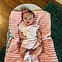 baby, infant, pink_blanket, smiling, bow, cute, laying_down, socks, lace, pastel_clothing, wooden_floor, green_rug, indoor, child, happy, soft_texture, baby_girl, portrait, comfortable, cozy