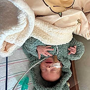 Christian is registered to the contest to win money with this photo: baby, infant, blanket, hospital, nasal_tube, pacifier, green_hoodie, fluffy_clothing, sleeping, bed, medical, cute, newborn, hand, face, person, child, soft_texture, comfort, resting