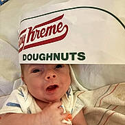 Christian joined the competition — help win amazing prizes! baby, infant, face, expression, blanket, fabric, doughnut_box, food_packaging, hand, lying_down, indoors, cute, cozy, soft, person, clothing, closeup, headwear, resting, newborn