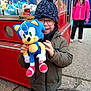 arcade, casual, child, claw_machine, concrete, crowd, game, glasses, happy, hat, jacket, outdoor, person, pink_jacket, plush_toy, smile, sonic_the_hedgehog, toy, winter_clothing, woman
