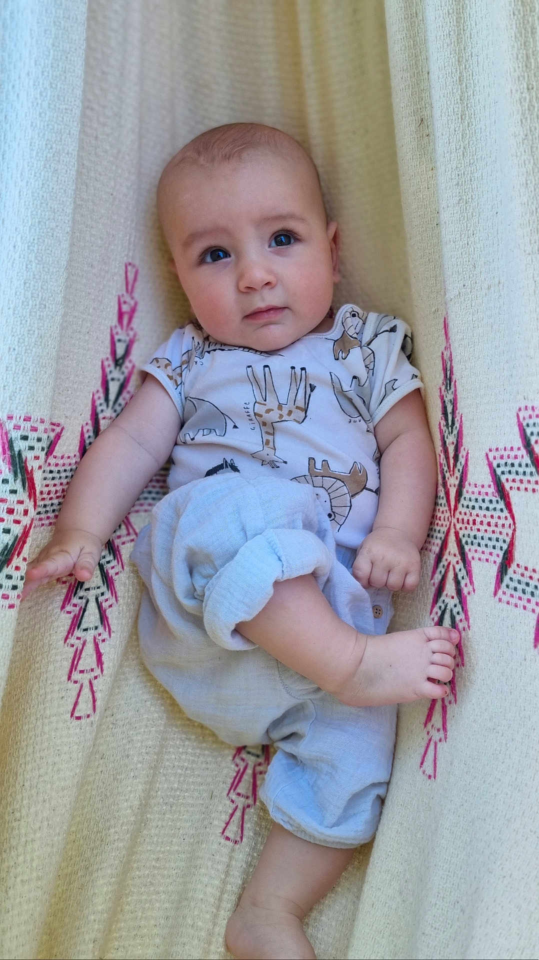 Gabriel is registered to the contest to win money with this photo: baby, infant, child, face, eyes, clothing, shirt, pants, blanket, pattern, texture, foot, hand, skin, portrait, indoor, cute, relaxed, looking_at_camera, sitting