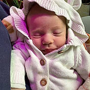 Madeline is registered to the contest to win money with this photo: baby, infant, hood, sweater, buttons, blanket, sleeping, closed_eyes, hand, pink_light, cozy, portrait, indoors, plant, storage_boxes, jar, seat, cute, newborn, hood_with_ears