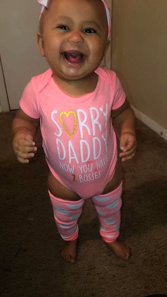 Penelope is registered to the contest to win money with this photo: arm, baby, baby_toddler_clothing, cheek, child, clothing, finger, happy, human_body, leg, magenta, mouth, neck, nose, person, pink, sleeve, smile, t_shirt, thigh