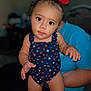 Kenzleigh is registered to the contest to win money with this photo: adult, baby, background, blurred, candid, child, curious, eyes, face, hair, hand, indoor, person, portrait, red_bow, skin, star_pattern, swimsuit, toddler, young_child