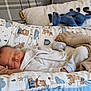 newborn, baby, sleeping, blanket, plush_toy, knitted_blanket, cushion, bed, clothing, infant, peaceful, cute, soft, indoors, resting, teddy_bear_pattern, cozy, child, portrait, cute_baby