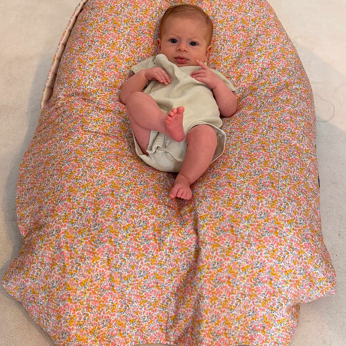 Hazel participe au concours pour gagner de l'argent avec cette photo : baby, child, clothing, comfort, cushion, cute, expression, floor, floral_pattern, foot, head, indoors, infant, looking, one_person, person, relaxing, sitting, skin, small