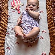 Hazel a rejoint le concours — aidez-le/la à gagner de superbes lots ! baby, basket, bassinet, blue_eyes, child, clothing, cute, face, foot, hand, hot_air_balloon, infant, lying_down, mattress, pattern, romper, skin, smile, wooden_toy, woven