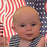 Larkin is registered to the contest to win money with this photo: american_flag, arms, baby, background, celebration, child, curious_expression, cute, decor, disco_ball, face, head, holiday, indoor, infant, person, portrait, skin, striped_clothing, table