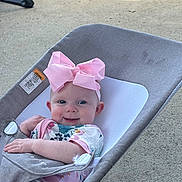 Larkin is registered to the contest to win money with this photo: baby, baby_girl, baby_rocker, child, colorful_clothing, comfort, cute, fabric, happy, headband, infant, outdoor, pink_bow, playful, portrait, relaxing, seated, smile, sunlight, young_child