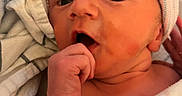 Kamdin is registered to the contest to win money with this photo: baby, beanie, bedding, blanket, child, close_up, cozy, eyes, face, finger, hand, hat, hospital, indoors, infant, newborn, nibbling, photography, portrait, swaddled