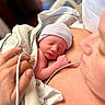 newborn, baby, sleeping, infant, parent, mother, hospital, birth, portrait, close_up, striped_hat, blanket, skin_to_skin, medical_monitor, monitoring_wire, hands, family, indoors, peaceful, tender