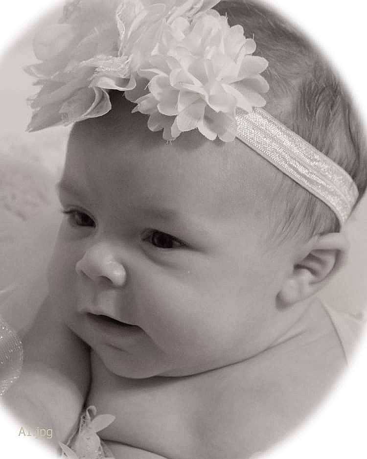Lilly is registered to the contest to win money with this photo: baby, baby_toddler_clothing, cap, ear, eyebrow, eyelash, hair_accessory, hairstyle, happy, head, headband, headgear, headpiece, iris, monochrome, monochrome_photography, person, petal, skin, toddler