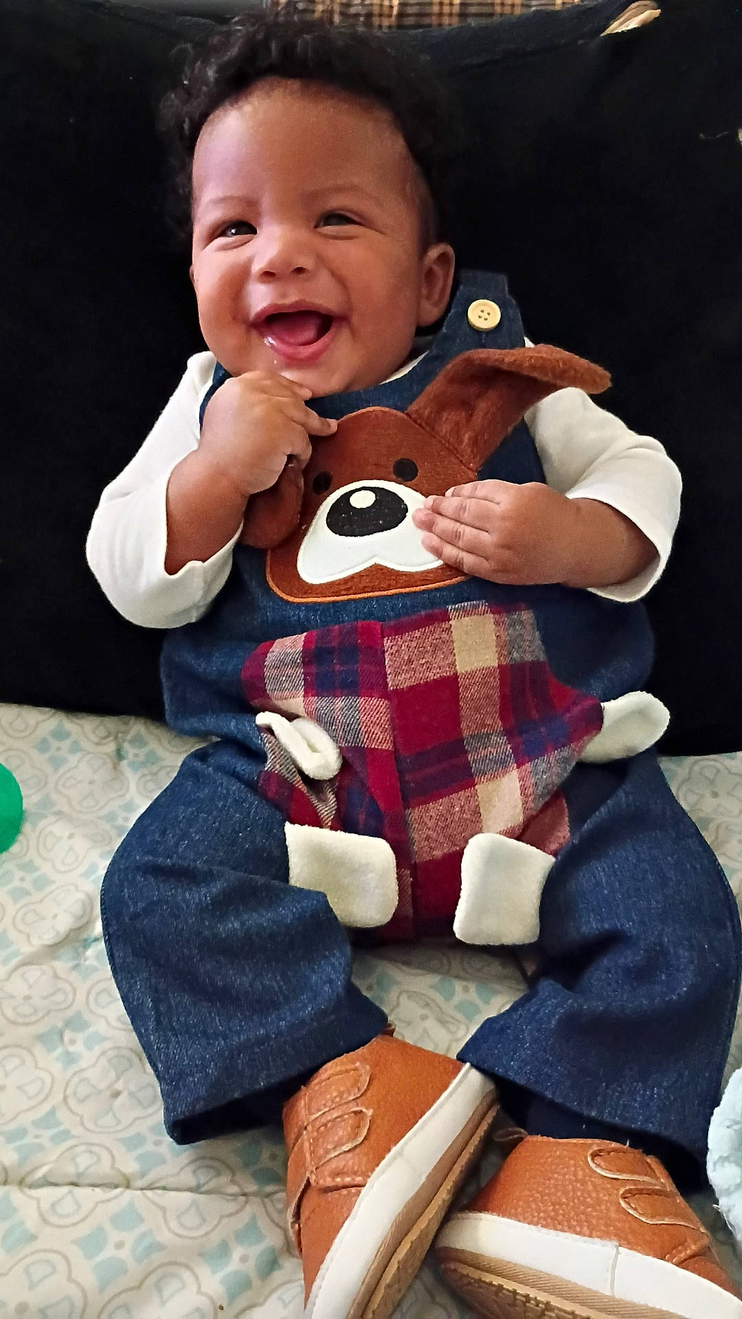 Jeriah joined the competition — help win amazing prizes! baby, blanket, brown_shoes, child, clothing, cute, denim, face, happy, indoors, infant, joy, overalls, pattern, person, plaid, playful, shoes, sitting, smile