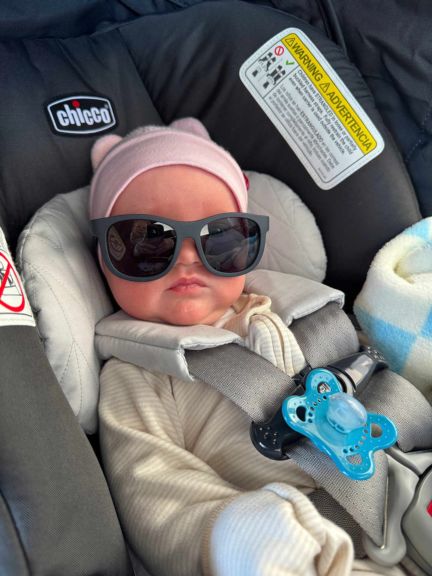 Lydia is registered to the contest to win money with this photo: baby, car_seat, sunglasses, pink_hat, pacifier, infant, child, seatbelt, clothing, cute, baby_girl, hat, gray_harness, indoor, portrait, baby_accessory, baby_clothes, car_interior, baby_face, relaxing