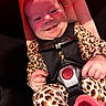 Remedy is registered to the contest to win money with this photo: baby, smiling, car_seat, child, infant, leopard_print, clothing, seatbelt, happy, portrait, young_child, cute, safety_harness, close_up, indoor, person, red_lighting, cheeky, hands, expression