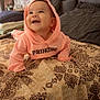baby, bed, blanket, child, clothing, cozy, cute, face, happy, head, home, hoodie, indoor, infant, patterned_bedspread, person, pillow, pink_clothing, smiling, toddler