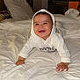 baby, bed, blanket, child, crawling, cute, furniture, happy, headwear, hoodie, indoors, infant, pajamas, person, portrait, room, sleeping_area, smile, white_clothing, young_child
