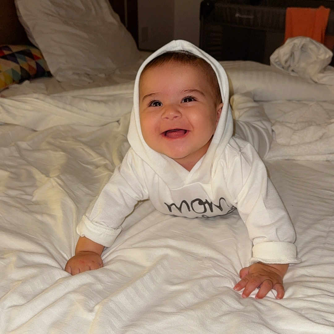 Manessa Ayna participe au concours pour gagner de l'argent avec cette photo : baby, bed, blanket, child, crawling, cute, furniture, happy, headwear, hoodie, indoors, infant, pajamas, person, portrait, room, sleeping_area, smile, white_clothing, young_child