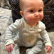 Julie is registered to the contest to win money with this photo: baby, infant, pajamas, carpet, dog, pet, indoor, child, smile, face, sitting, cute, animal, furniture, pattern, cozy, young, portrait, friendship, home