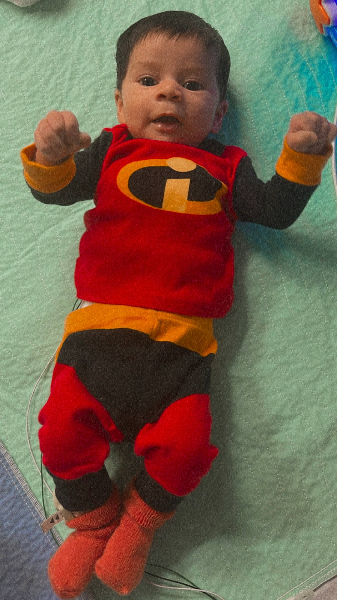 Aron is registered to the contest to win money with this photo: arm, baby, baby_toddler_clothing, child, fictional_character, finger, flooring, fun, hand, head, human_leg, orange, pattern, person, personal_protective_equipment, red, sleeve, stuffed_toy, thigh, thumb