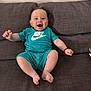 arm, baby, casual, child, clothing, couch, cute, feet, furniture, happy, indoor, infant, joyful, nike, person, shorts, sitting, smiling, tshirt, young