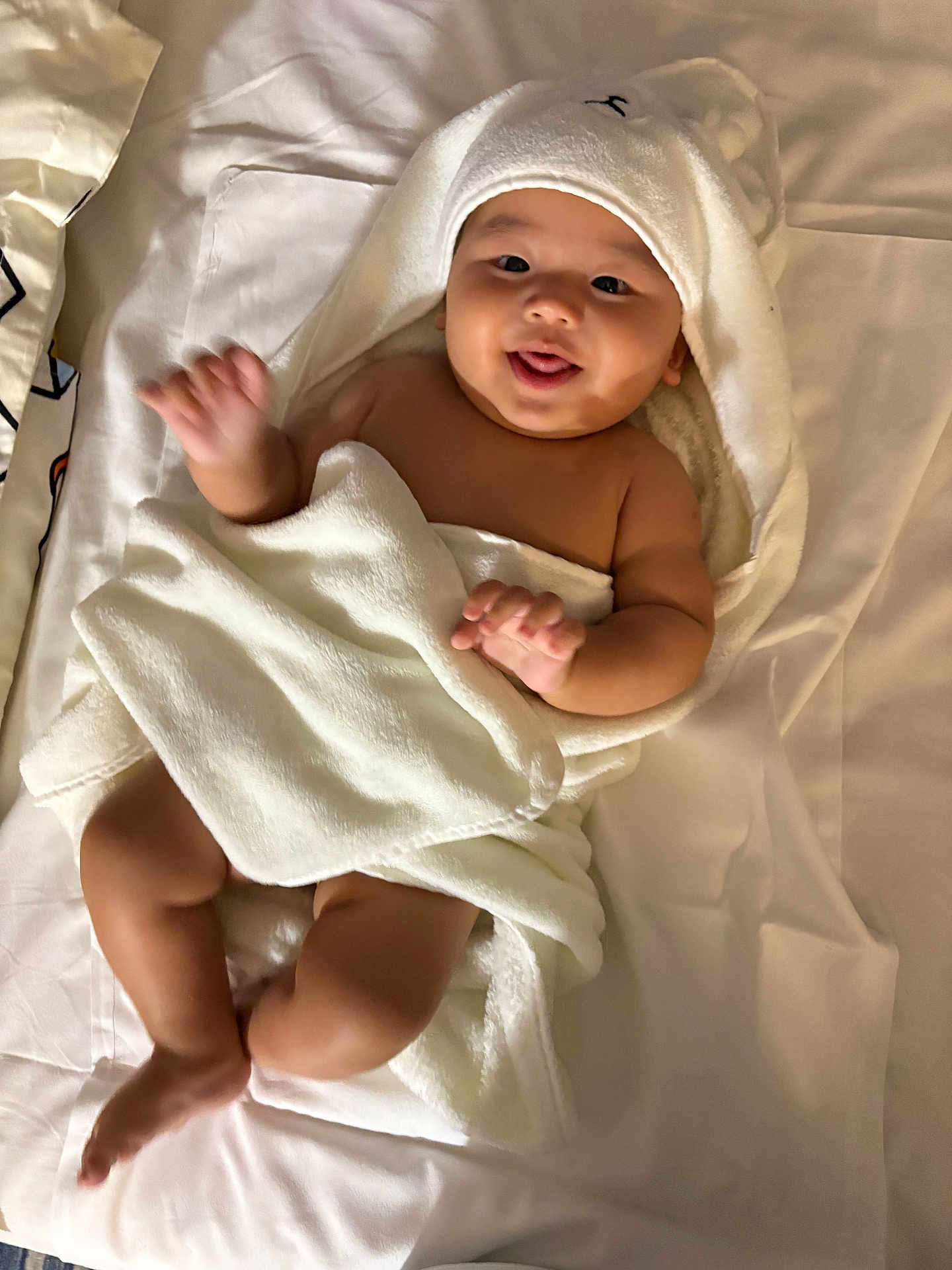Muhammad is registered to the contest to win money with this photo: baby, towel, bed, white, blanket, child, cute, smiling, tongue_out, infant, soft, sleepwear, happy, playful, skin, lying_down, indoors, hooded_towel, person, newborn