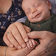 Jacob is registered to the contest to win money with this photo: baby, smiling, sleeping, hands, tattoo, ring, bracelet, adult, child, closeup, portrait, love, family, skin, clothing, fabric, holding, peaceful, toddler, comfort