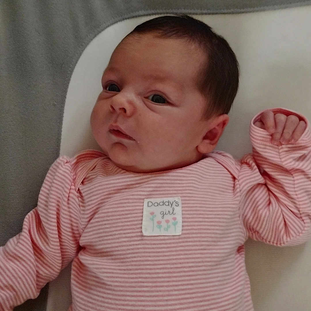 Kailee Jo is registered to the contest to win money with this photo: baby, blanket, child, cozy, cute, expression, face, hand, head, indoors, infant, lying_down, newborn, person, pink_clothing, portrait, sleepwear, soft_surface, striped_pajamas, young