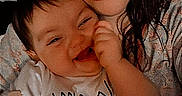 Kailee is registered to the contest to win money with this photo: adult, baby, bed, blanket, casual_photo, chewing, close_up, cuddling, family, hand, happy, indoors, infant, mother, patterned_clothing, portrait, selfie, smiling, tongue_out, white_shirt