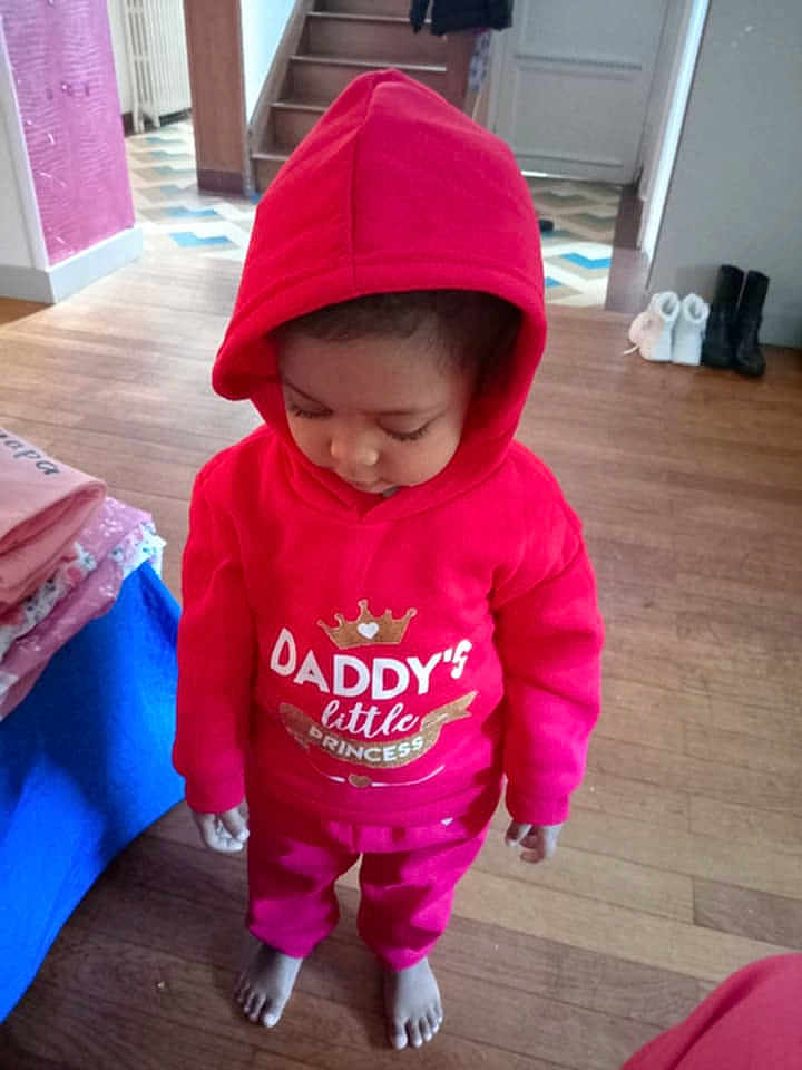 Elea a rejoint le concours — aidez-le/la à gagner de superbes lots ! toddler, child, hoodie, red_clothing, barefoot, indoor, wooden_floor, stairs, boots, folded_clothes, person, looking_down, casual_wear, cute, young_child, home, flooring, sweatshirt, pants, cozy