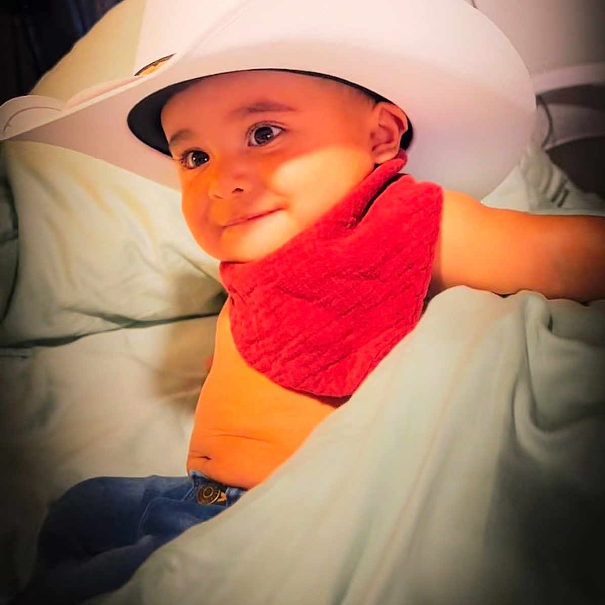 Kenai joined the competition — help win amazing prizes! baby, bed, blanket, child, clothing, cowboy_hat, cute, face, happy, headwear, indoor, jeans, person, portrait, red_bandana, relaxed, skin, smile, toddler, young_child