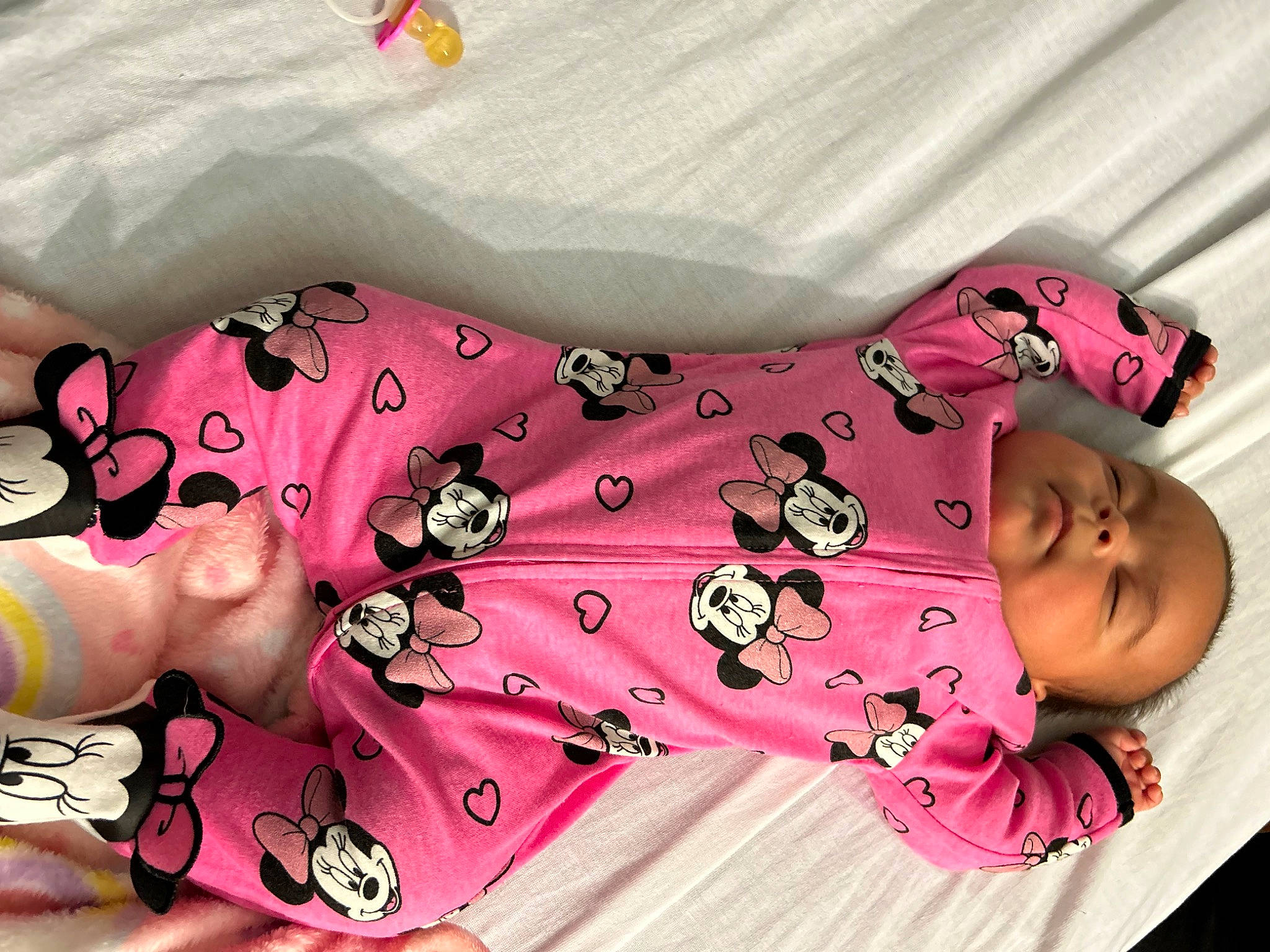 Amelia is registered to the contest to win money with this photo: baby_toddler_clothing, bedding, child, comfort, fashion_accessory, happy, human_leg, linens, magenta, pattern, peach, person, pink, skin, sleeve, textile, thigh, toddler, visual_arts, white