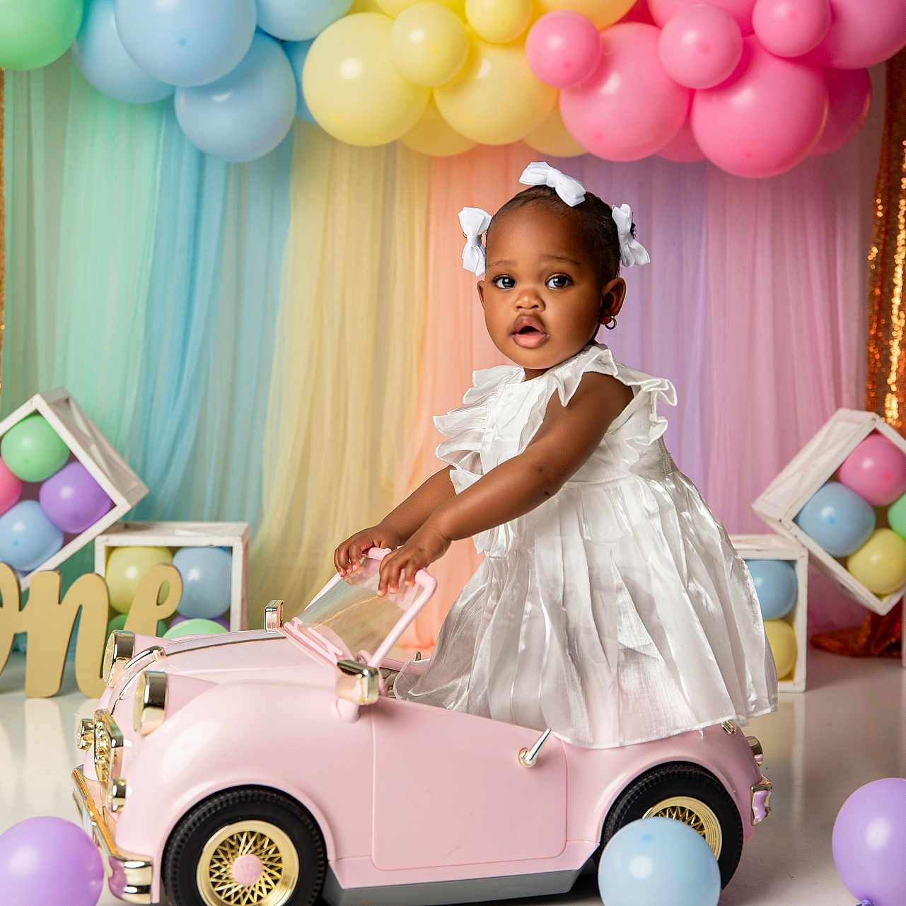 Ruby joined the competition — help win amazing prizes! toddler, child, toy_car, balloons, party, celebration, dress, white_dress, pink_car, pastel_colors, golden_backdrop, cute, indoor, smiling, decorations, birthday, one_year, ribbons, happy, young_child