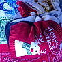 cat, black_and_white, sleeping, curled_up, christmas_sweater, red_sweater, snowman_design, blanket, patterned_blanket, cozy, indoor, resting, pet, feline, warm, cute, holiday, festive, animal, relaxed