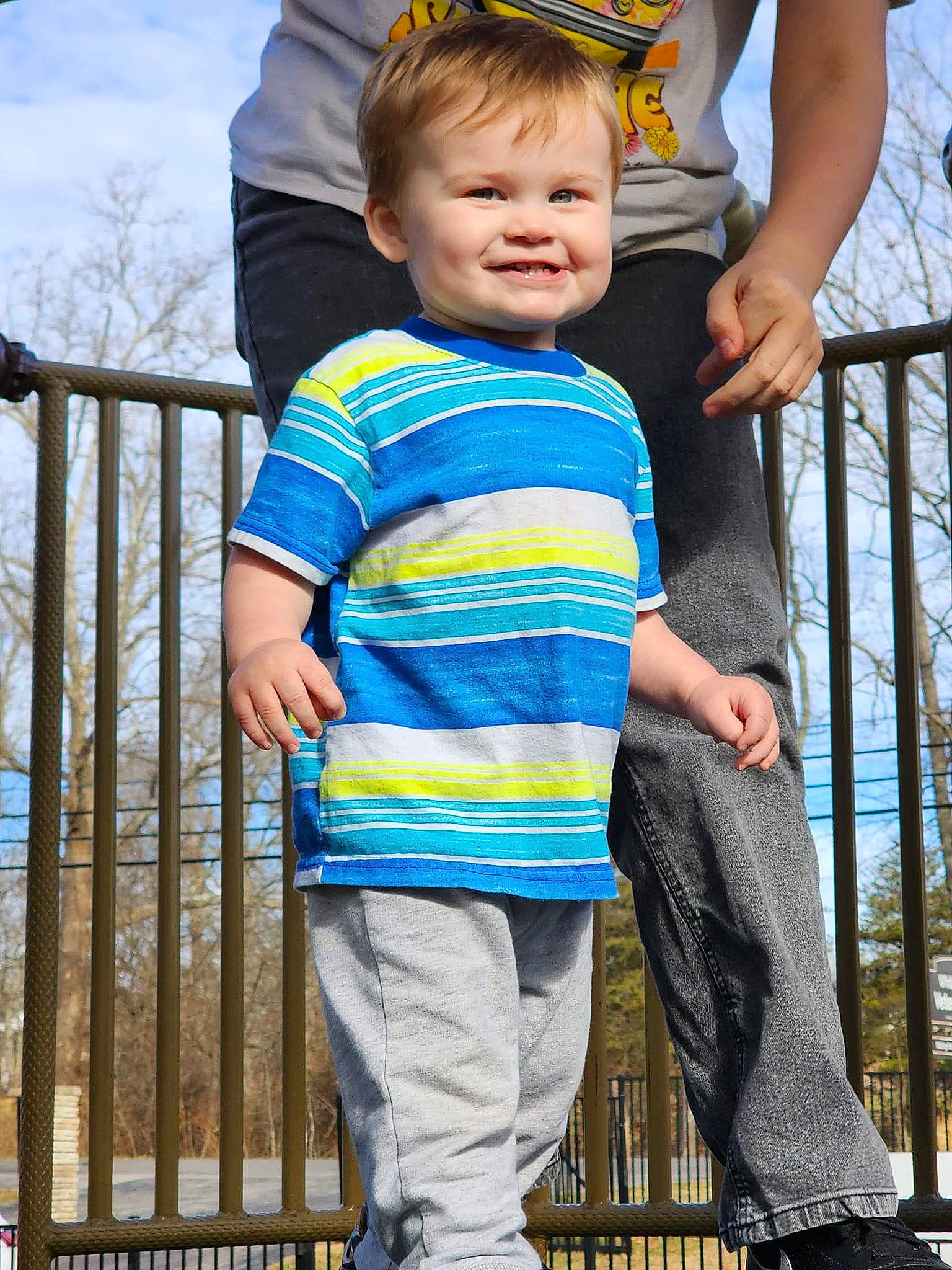 Malakai is registered to the contest to win money with this photo: baby_toddler_clothing, child, cloud, cool, denim, electric_blue, fence, grass, hair, happy, joy, leisure, people, person, sky, sleeve, standing, t_shirt, textile, toddler