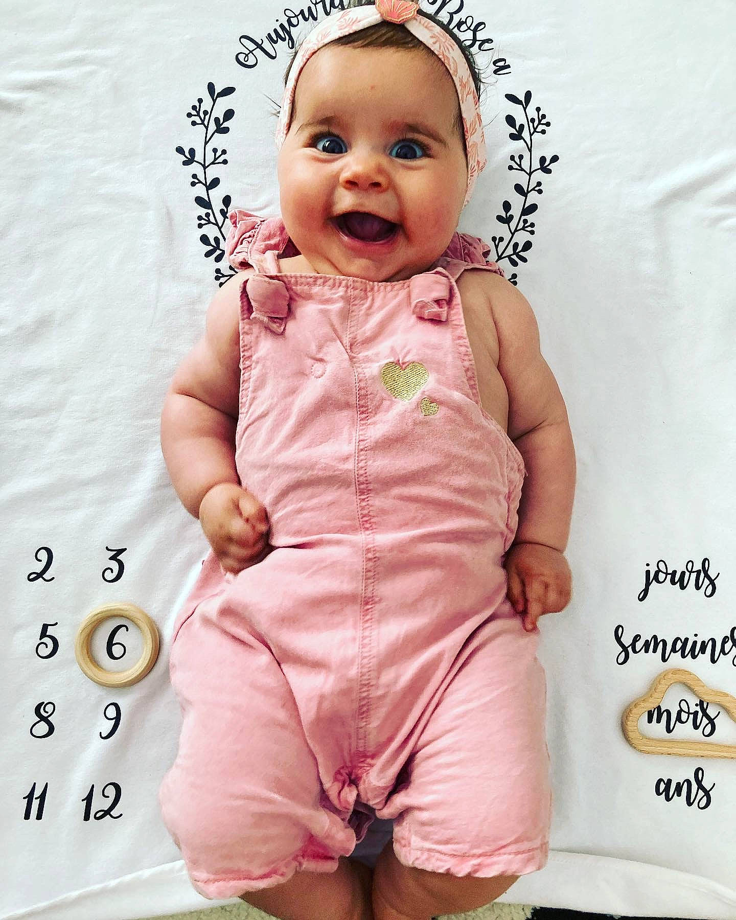 Rose participe au concours pour gagner de l'argent avec cette photo : baby, baby_toddler_clothing, cheek, face, font, gesture, happy, head, magenta, nose, one_piece_garment, pattern, person, pink, product, skin, sleeve, smile, thumb, toddler