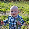 baby, child, outdoor, grass, greenery, plaid_shirt, blue_shirt, leaf, nature, sunlight, person, young_child, cute, portrait, standing, holding, expression, daylight, head, face