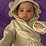 Ahmed Adam is registered to the contest to win money with this photo: baby, child, robe, hood, bear_ears, purple_blanket, infant, cute, cozy, fist, face, person, lying_down, soft_texture, warm_clothing, indoor, portrait, young, adorable, sleepwear