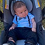 baby, infant, car_seat, outdoor, grass, clothing, black_pants, bow_tie, onesie, shoes, footwear, person, young_child, cute, portrait, sitting, sunlight, expression, head, face