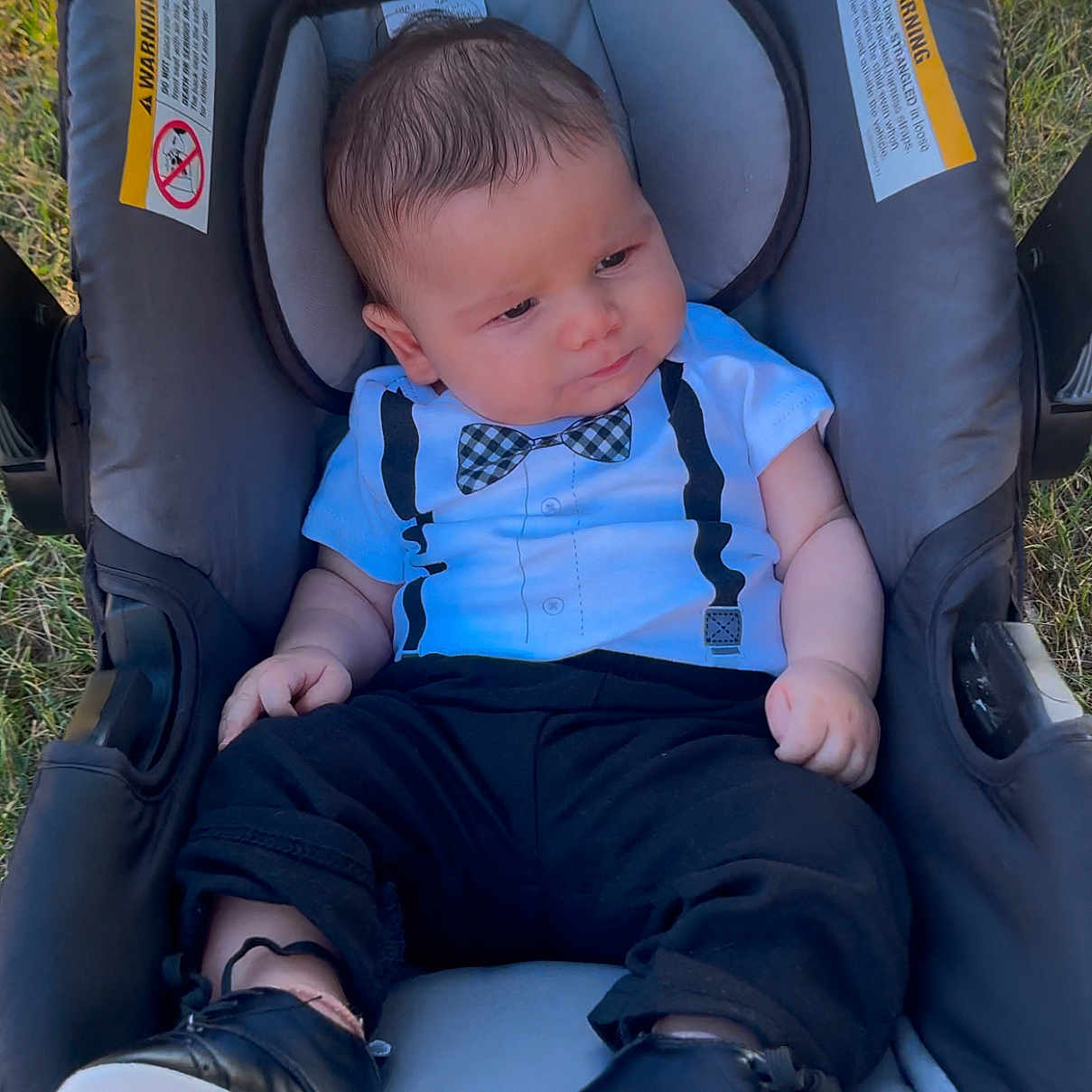 Ahmed Adam is registered to the contest to win money with this photo: baby, black_pants, bow_tie, car_seat, clothing, cute, expression, face, footwear, grass, head, infant, onesie, outdoor, person, portrait, shoes, sitting, sunlight, young_child
