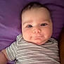 baby, child, face, striped_shirt, purple_background, cute, smile, infant, portrait, lying_down, chubby_cheeks, skin, eyes, head, person, young, toddler, clothing, baby_girl, baby_boy
