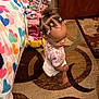 toddler, child, hair_beads, barefoot, carpet, bedspread, hearts, toy_box, shoes, indoor, curly_hair, patterned_rug, colorful, room, floor, clothing, standing, looking_down, cute, young_child